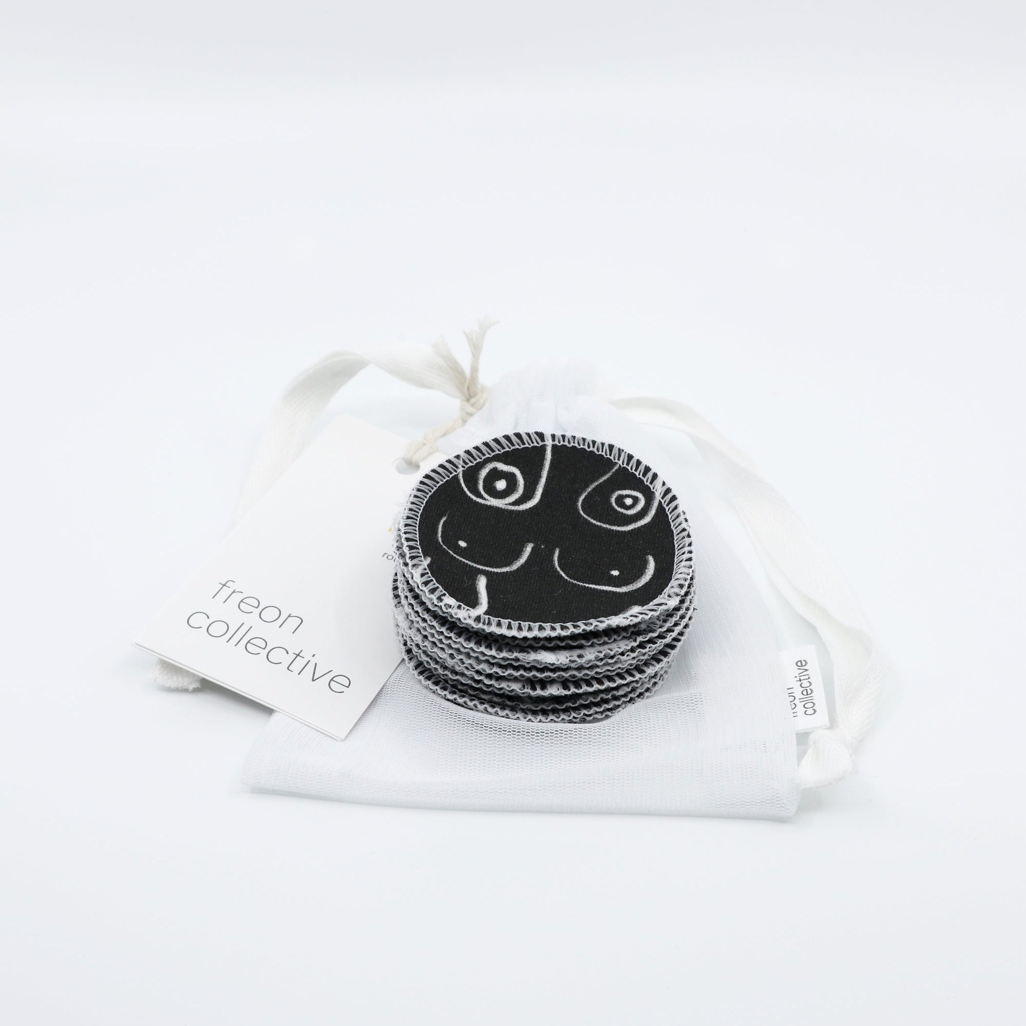 Black and white resuable cotton makeup pads on a white cloth by Freon Collective with case