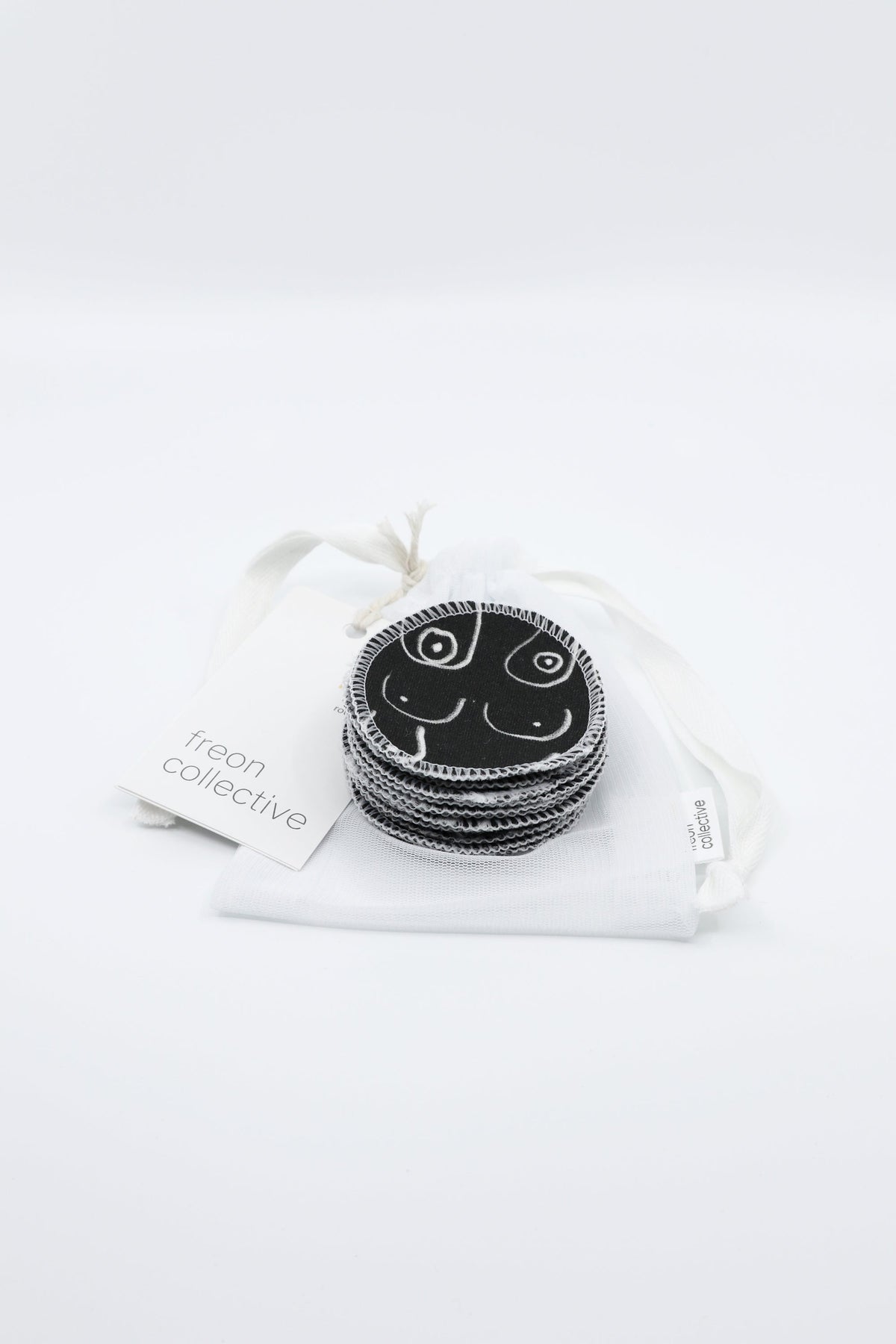 Black and white resuable cotton makeup pads on a white cloth by Freon Collective with case