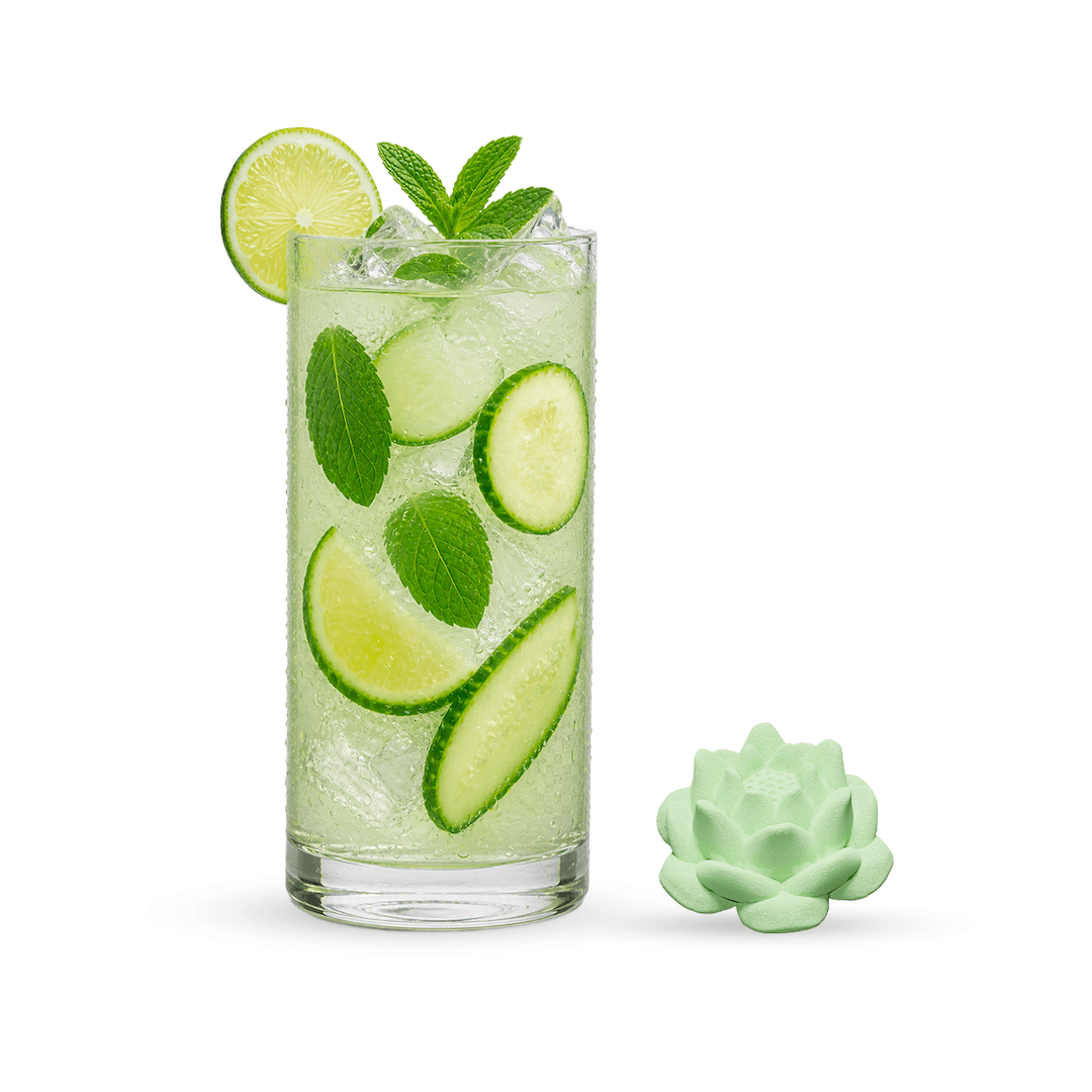 Glass of green cocktail with lime and cucumber slices on a white background