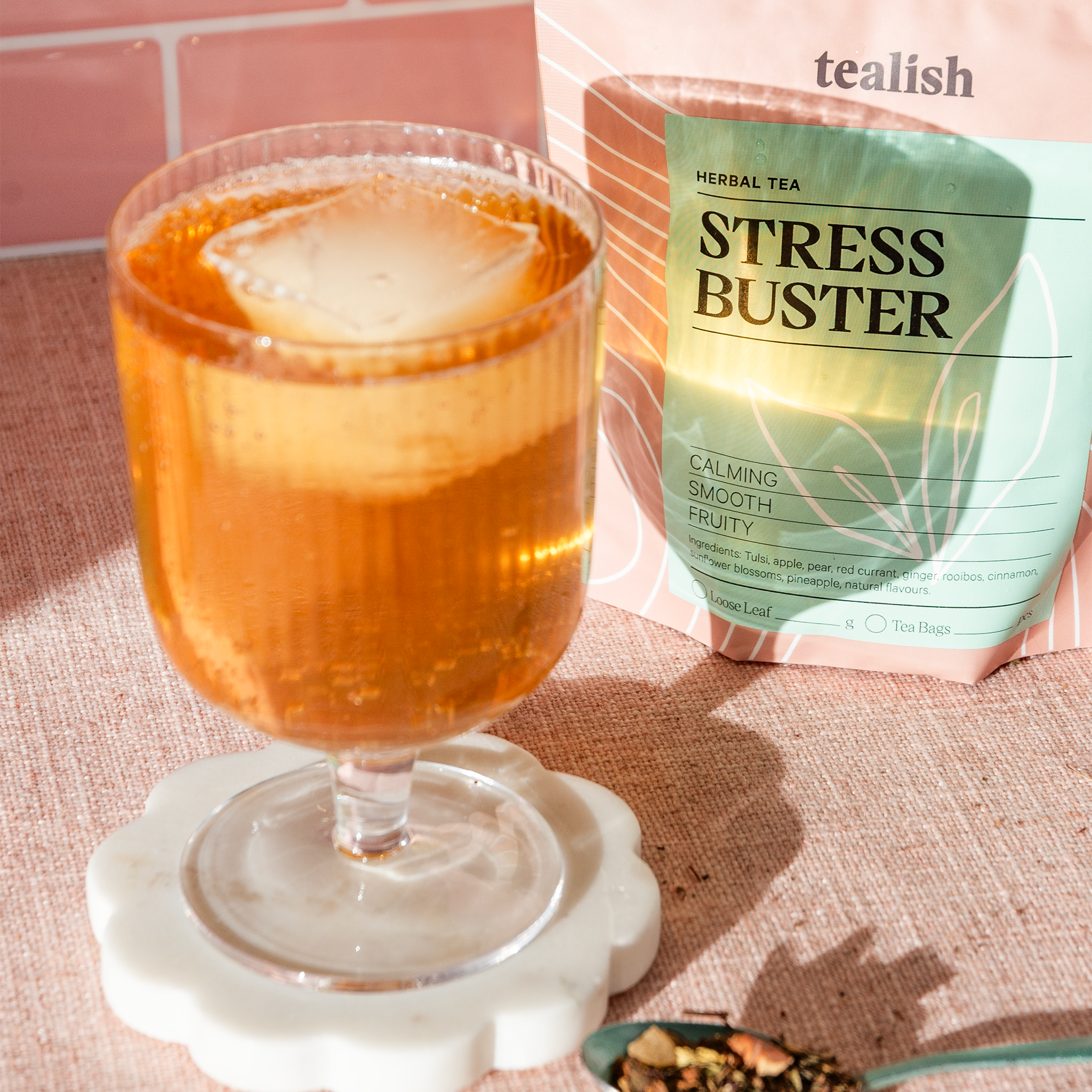 Glass of iced tea next to a 'Stress Buster' herbal tea package on a textured surface.