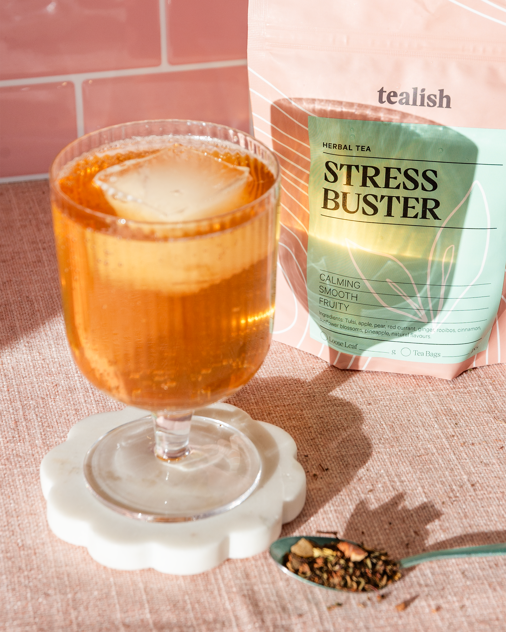 Glass of iced tea next to a 'Stress Buster' herbal tea package on a textured surface.