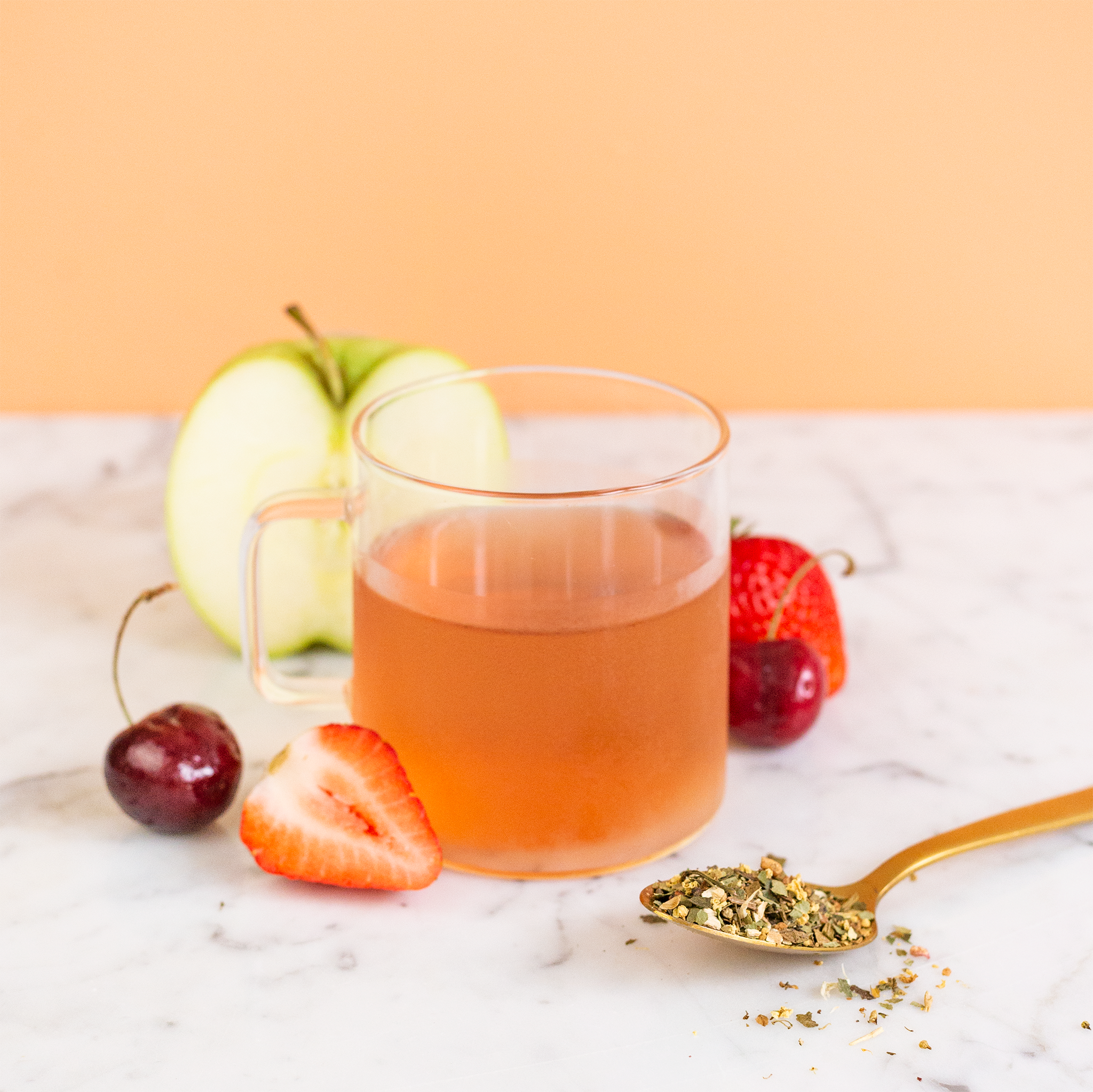 Glass of iced tea with fruits and a spoon on a marble surface