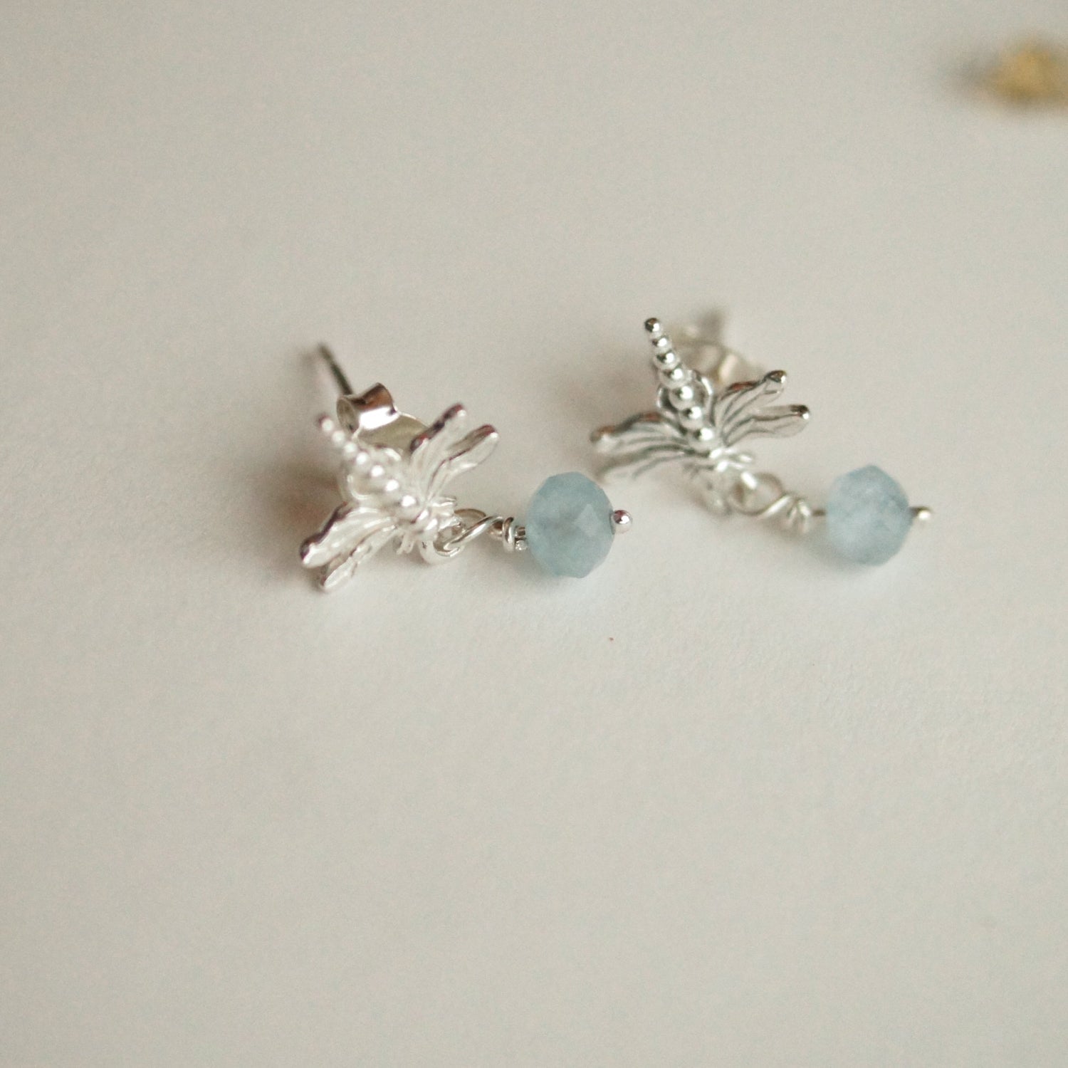 Silver earrings with light blue beads on a beige background