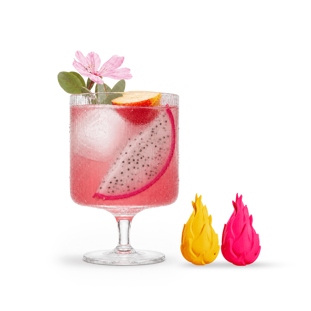 Pink mocktail with dragon fruit and a flower in a glass, next to two dragon fruit slices on a white background