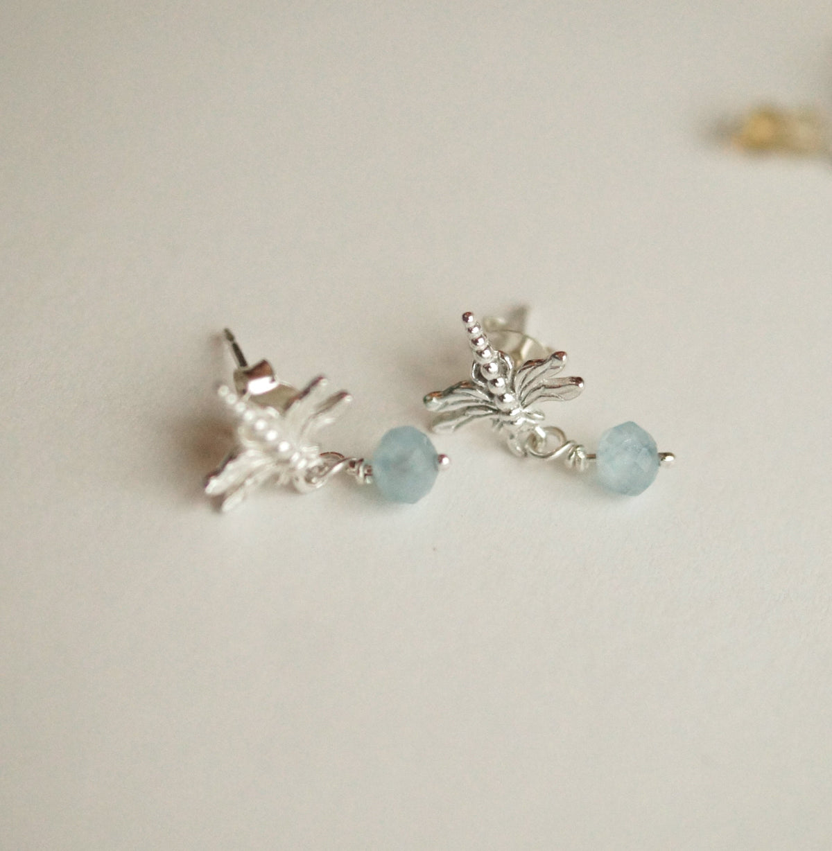 Silver earrings with light blue beads on a light background