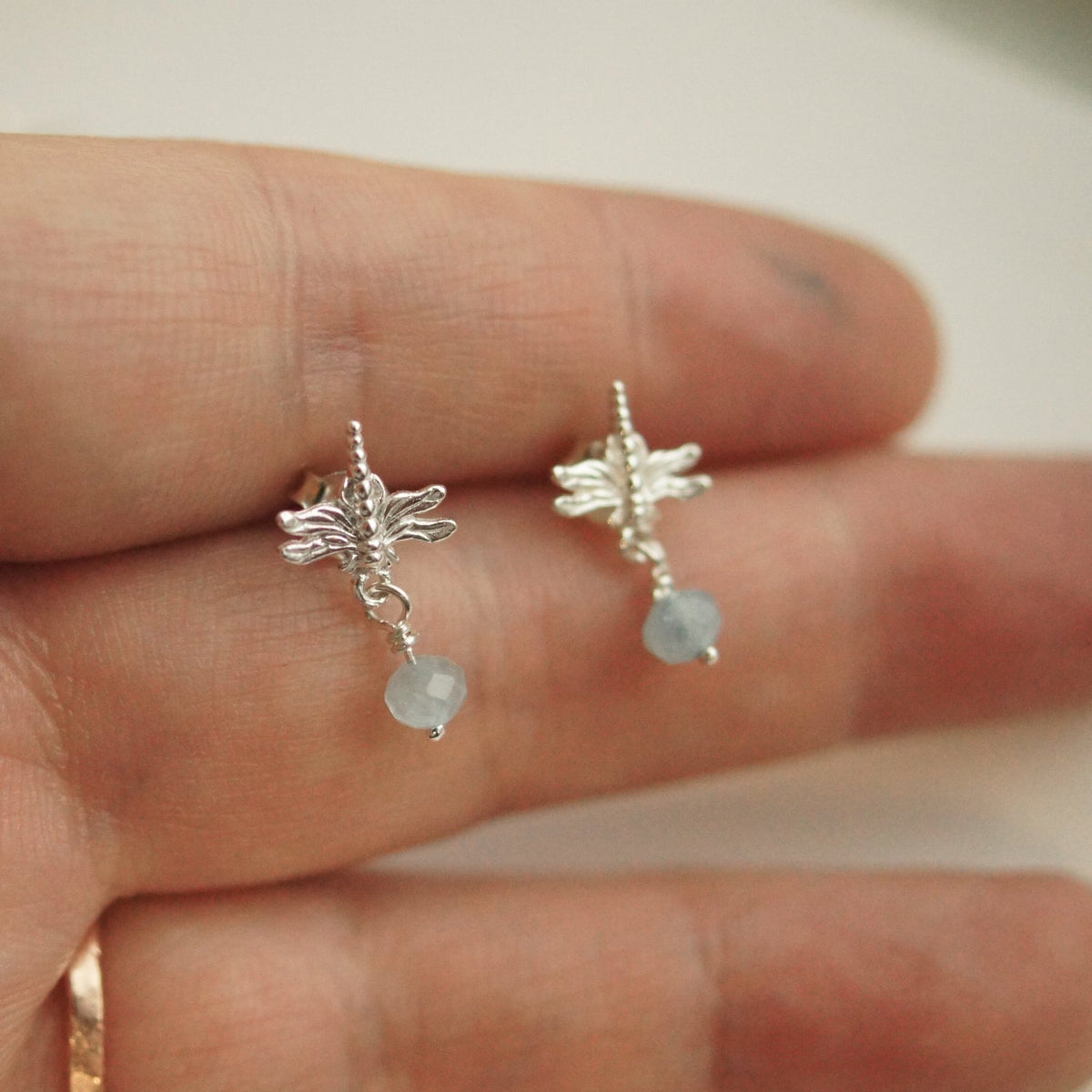 Silver fairy earrings with a small gemstone on a hand