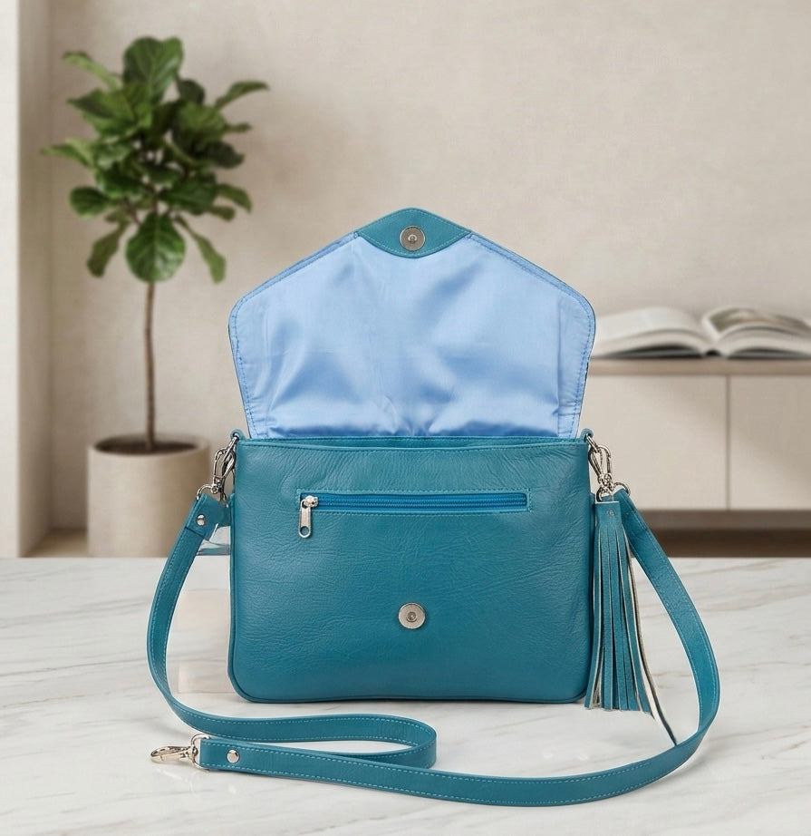 OldTribes Blue handbag with open top on a light surface, plant and book in the background