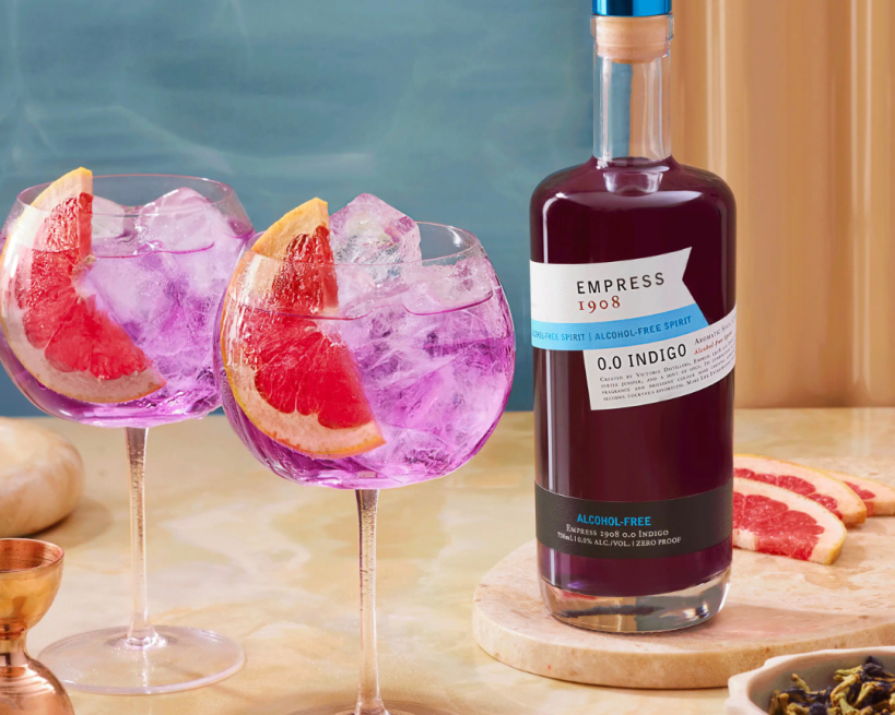 Bottle of Empress 1908 alcohol-free gin with two pink cocktails and grapefruit slices on a table. The Sobr Market