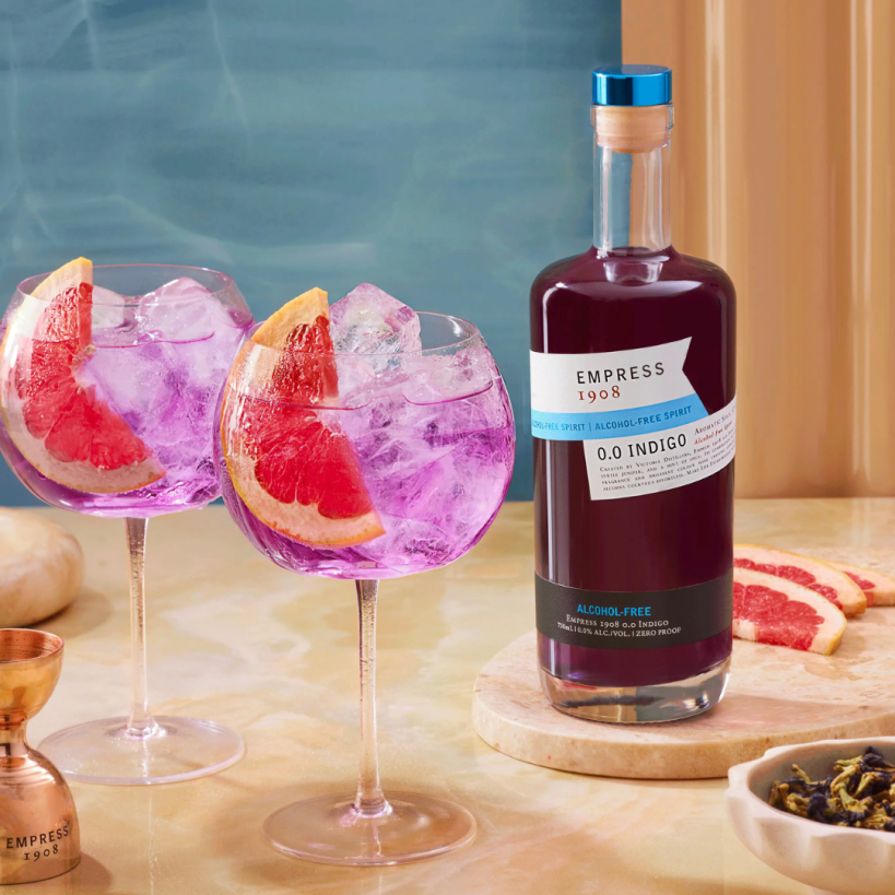 Bottle of Empress 1908 alcohol-free gin with two pink cocktails and grapefruit slices on a table. The Sobr Market