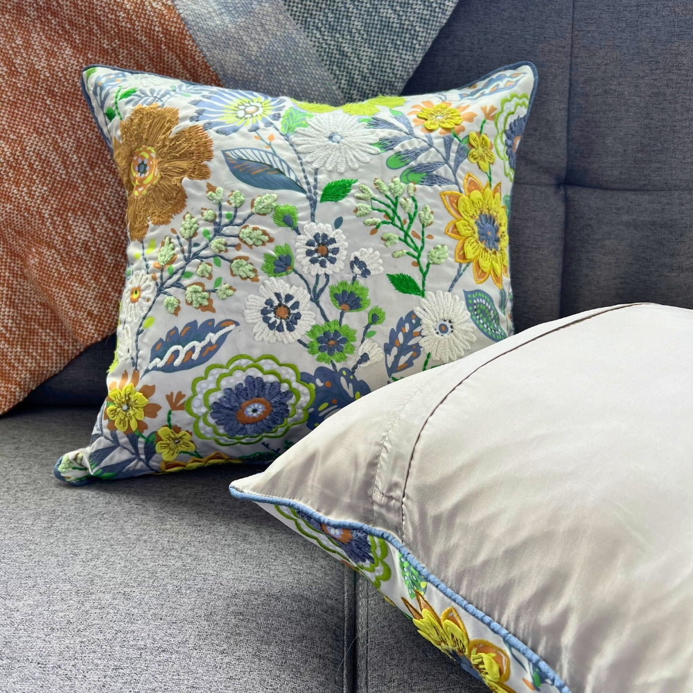 Decorative floral pillow on a gray sofa with other pillows.