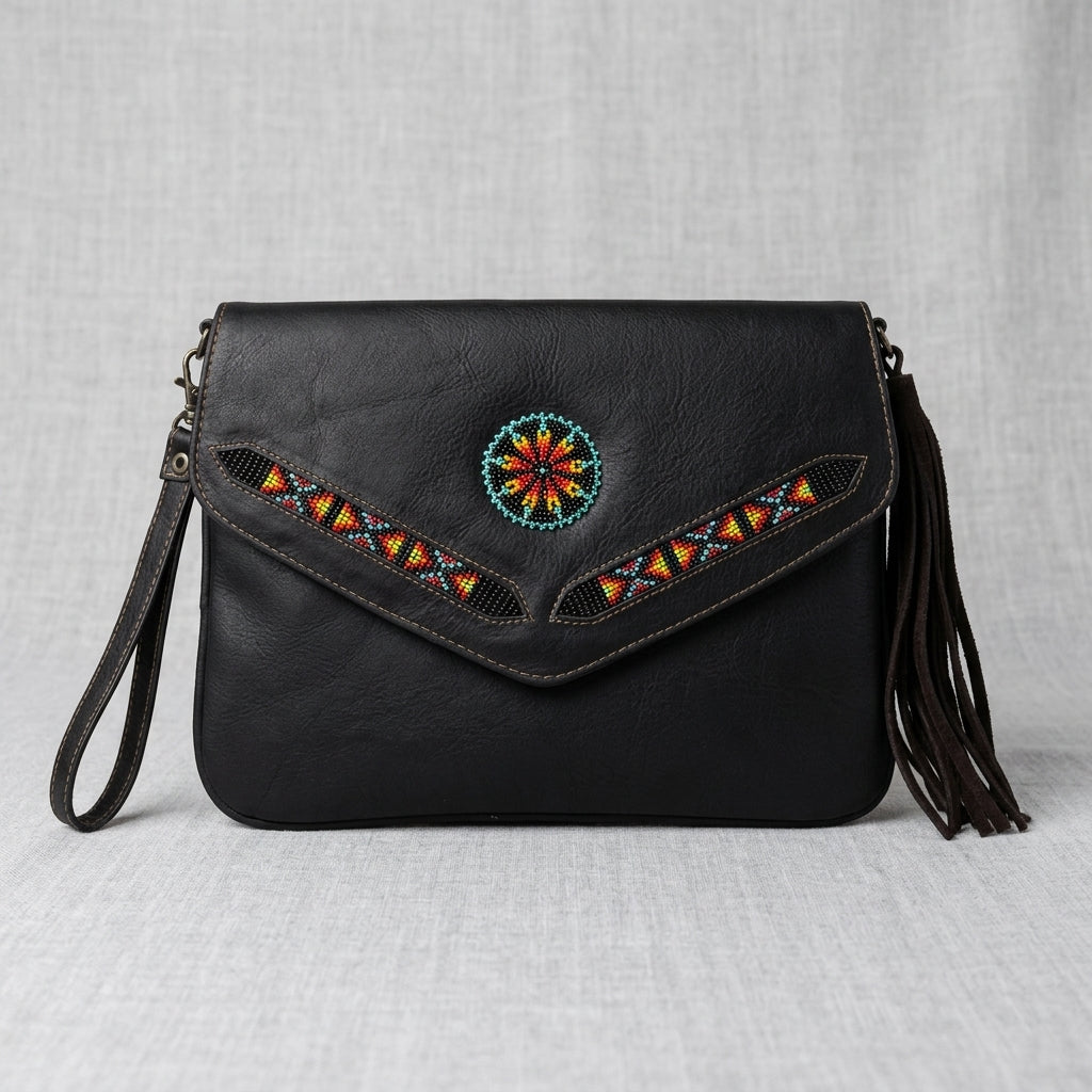 Black leather crossbody bag with a flap closure, featuring a colorful circular beadwork motif and geometric beaded accents on the front flap, along with dark brown leather tassels on the side, set against a light gray textured fabric background.