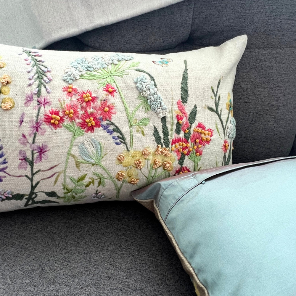 Decorative pillow with floral embroidery on a gray sofa.