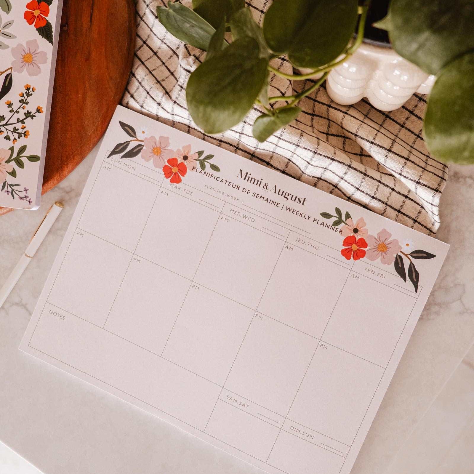 Floral planner sheet on a desk with a plant and decorative items