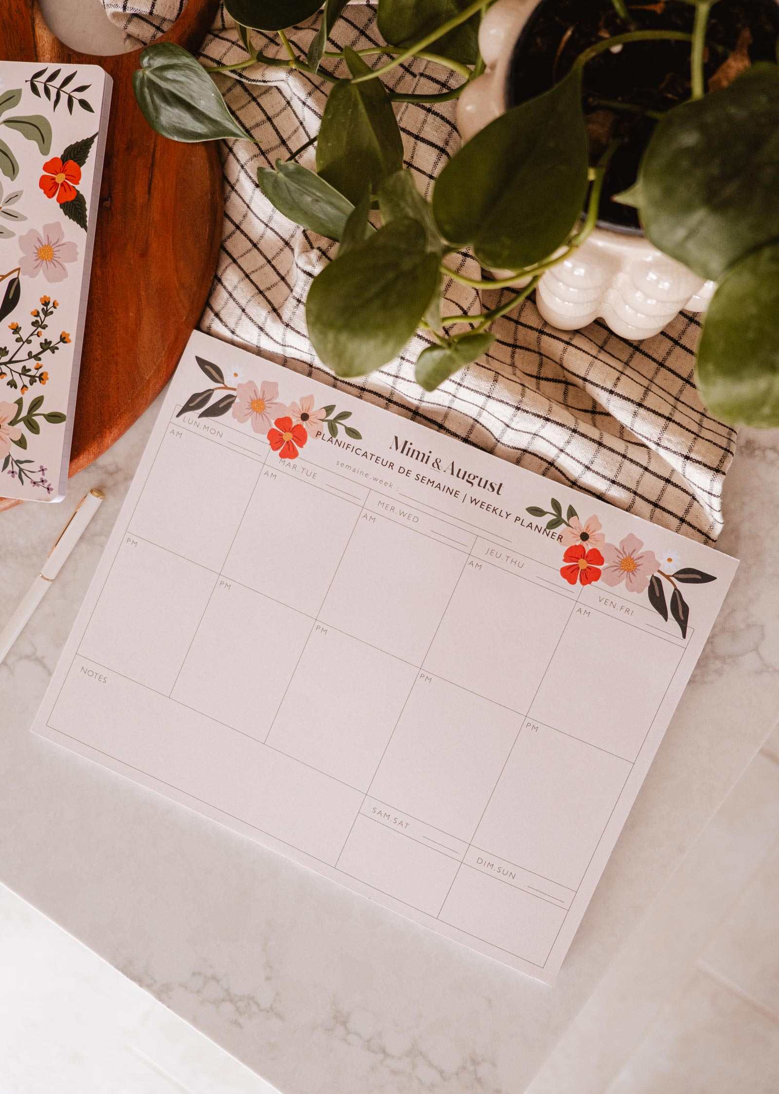 Floral planner sheet on a desk with a plant and decorative items