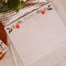 Floral-themed calendar on a marble surface with a pen and plant.