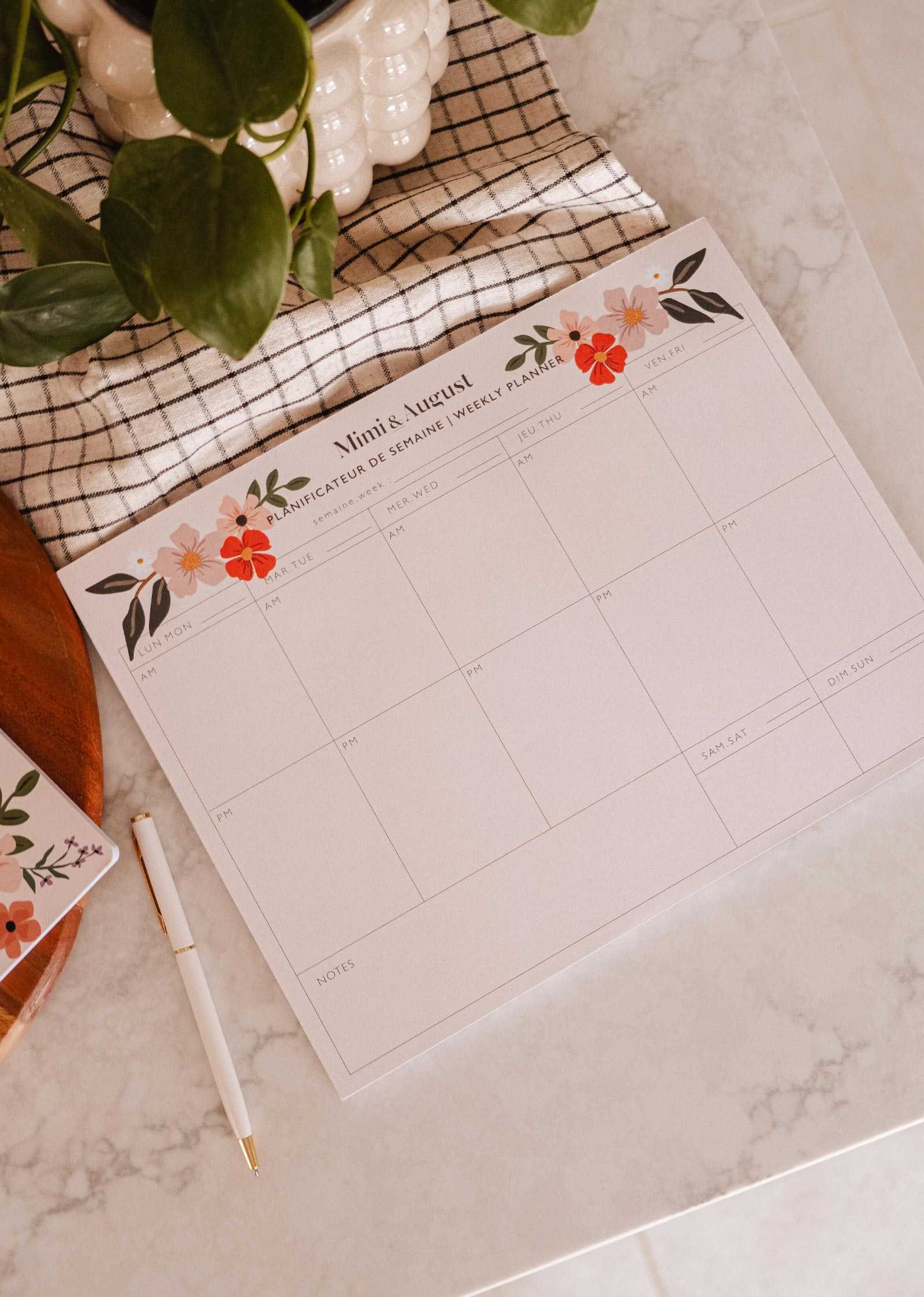 Floral-themed calendar on a marble surface with a pen and plant.