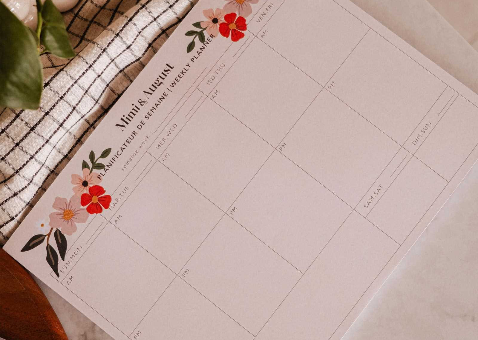 Floral planner sheet on a marble surface with a pen and plant.