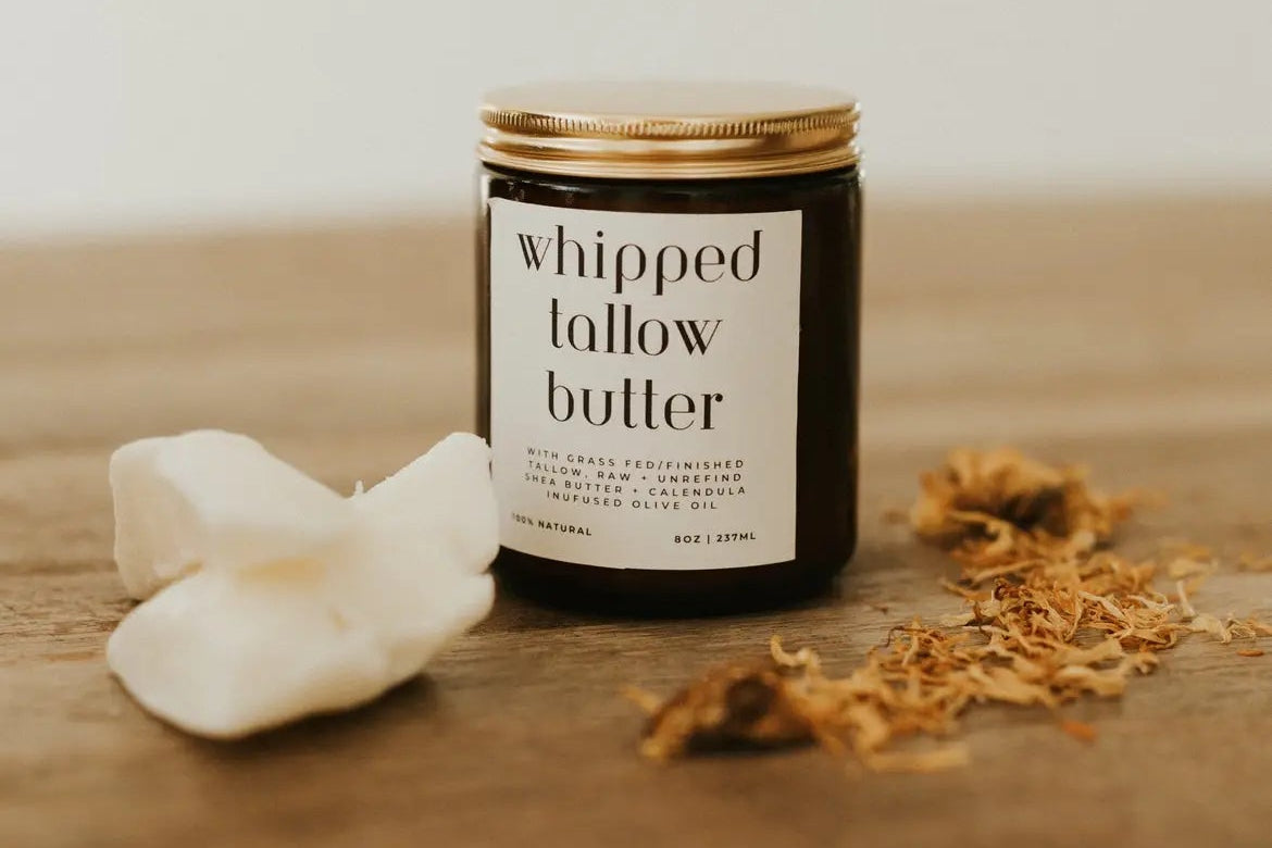 Jar of whipped tallow butter on a wooden surface with flowers.