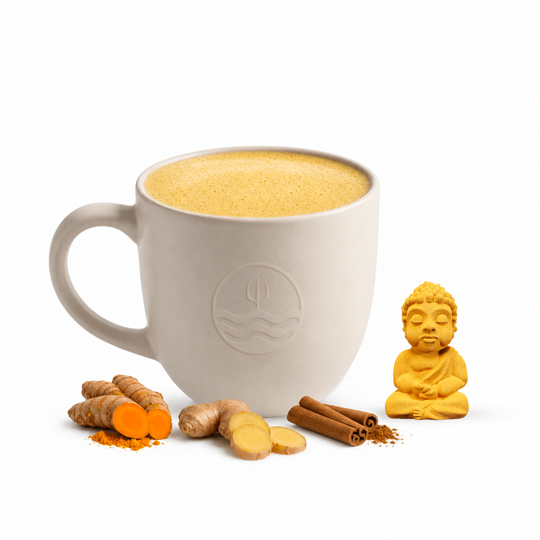 A light beige ceramic mug filled with a frothy golden drink, styled with turmeric root, ginger slices, cinnamon sticks, and a small yellow Buddha figurine on a white background. Posiedn Golden Milk bomb flavor bomb