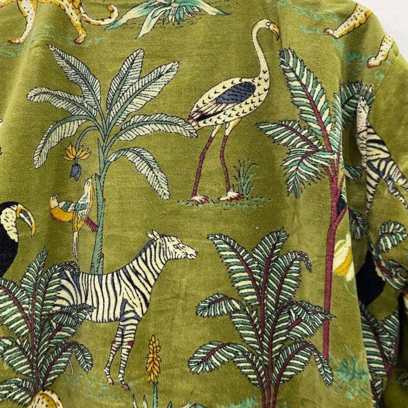 Close-up of lush green jungle print with exotic animals on velvet kimono, showcasing organic cotton handmade craftsmanship.