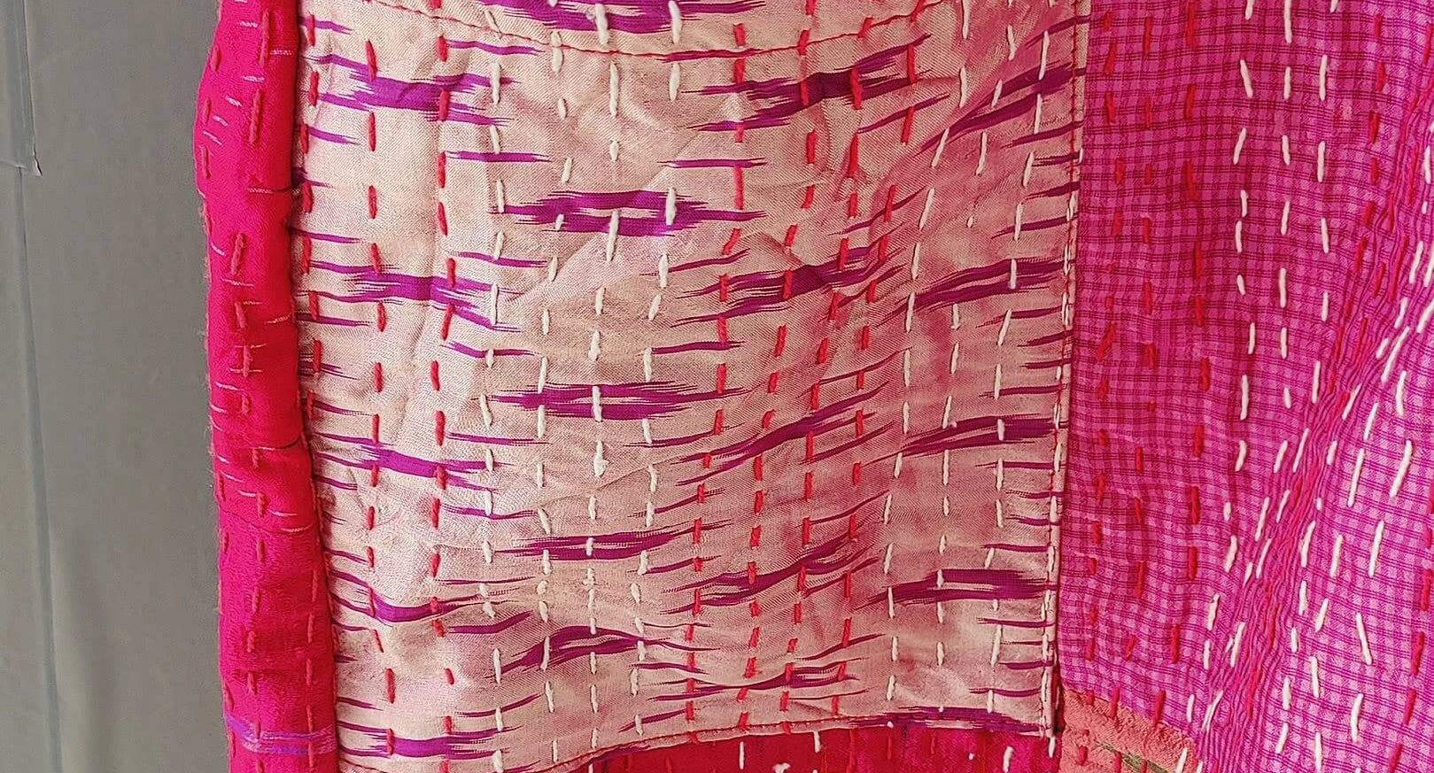 Close-up of a silk quilted kimono with vibrant pink patterns and a pocket, showcasing handmade Kantha craftsmanship.