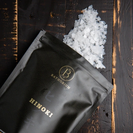 Black package labeled 'Hinoki' with a small pile of white crystals on a wooden surface.