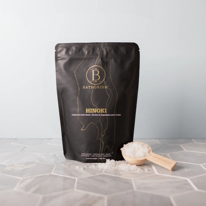 Batherium Hinoki product packaging with a scoop of product on a textured surface