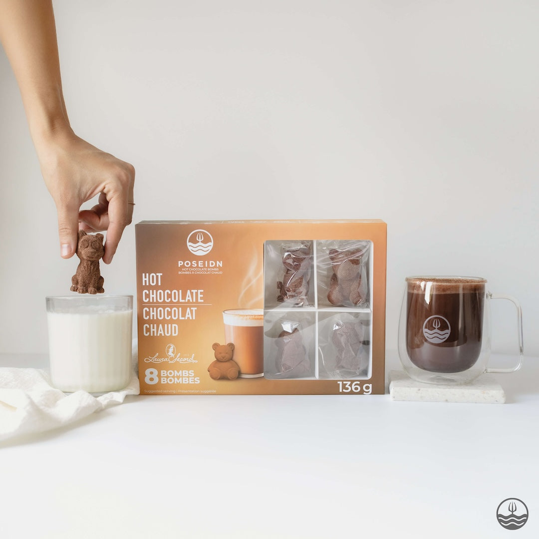 Hot chocolate bomb packaging with a hand holding a bomb, a mug of hot chocolate, and a candle.