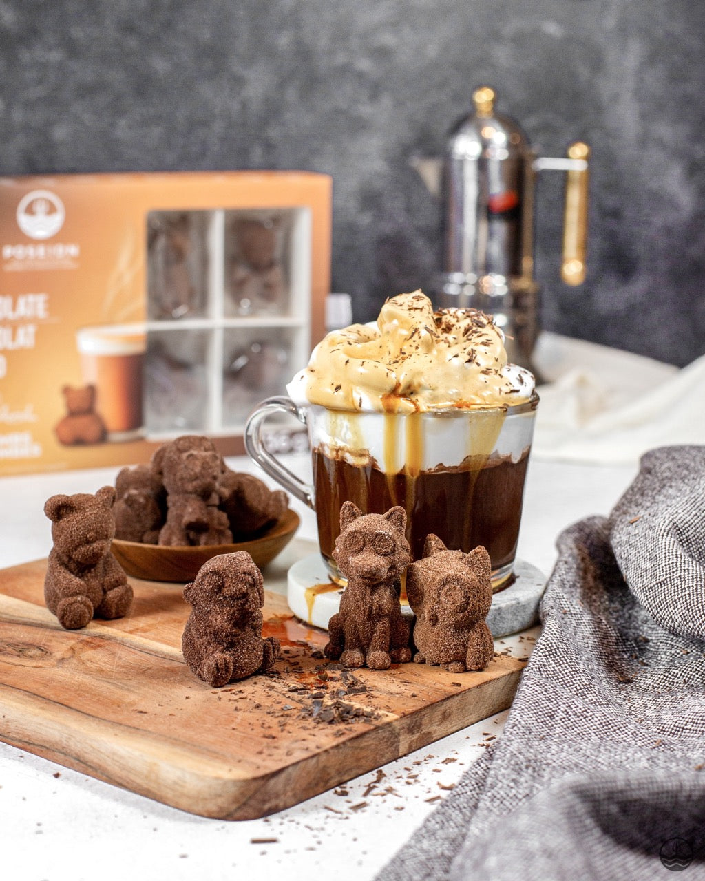 Chocolate bear figurines on a wooden board with a hot chocolate drink in the background.