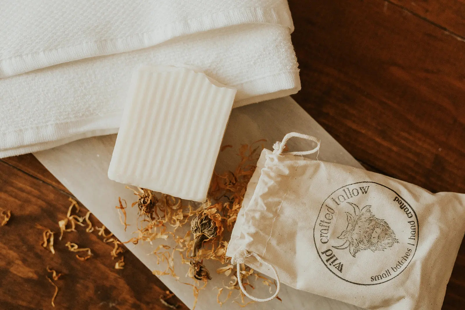 Bar of soap, towel, and small bag on a wooden surface with 'crafted tallow' branding.