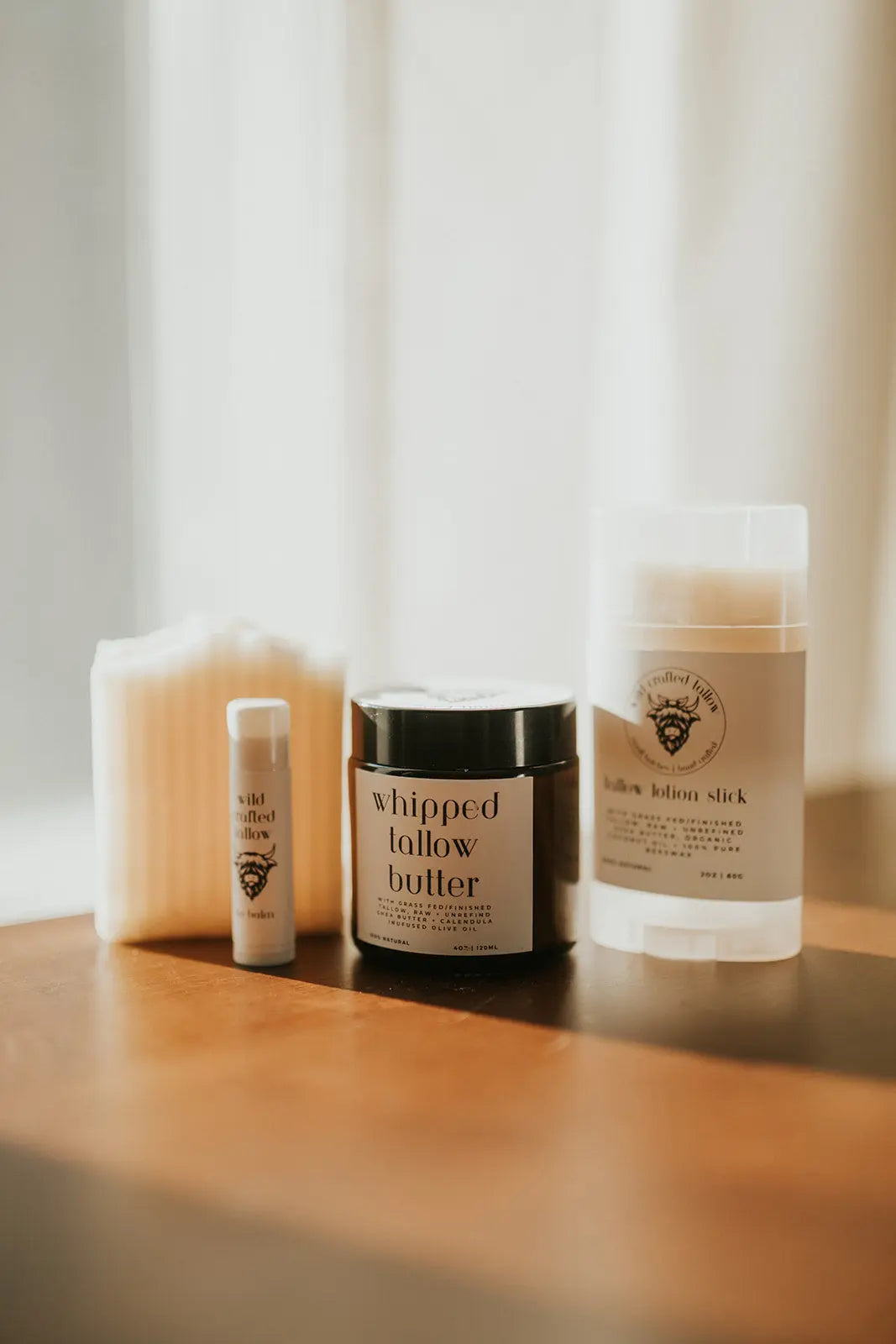 Skincare products including a jar of 'whipped follow butter' on a wooden surface with a soft, blurred background.