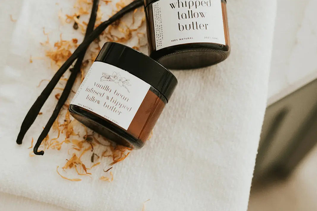 Two containers of whipped butter on a white towel with a vanilla bean.