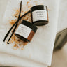 Two containers of whipped butter on a white towel with a vanilla bean.
