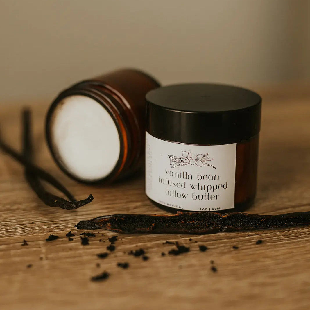 Vanilla bean infused whipped body butter jar on a wooden surface with vanilla beans around