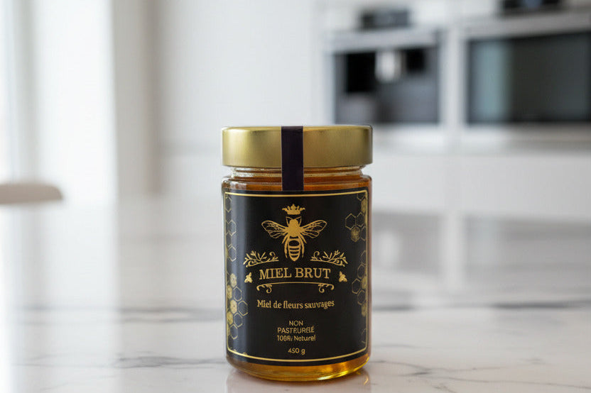 Jar of honey with a black label on a marble countertop in a kitchen.