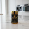 Jar of honey with a black label on a marble countertop in a kitchen.
