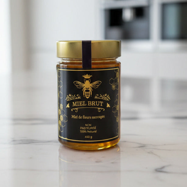 Jar of honey with a black label on a marble countertop in a kitchen.