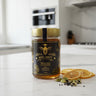 Jar of Miel Brut honey on a kitchen counter with dried oranges and cardamom pods.