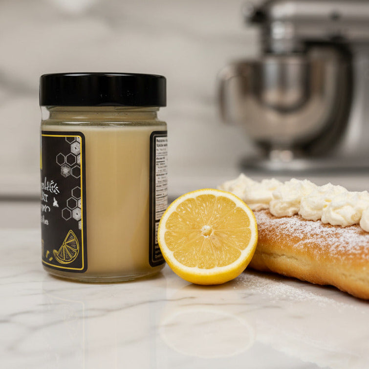 Jar of lemon cream, lemon slice, and cream-filled pastry on a kitchen counter with a stand mixer in the background.