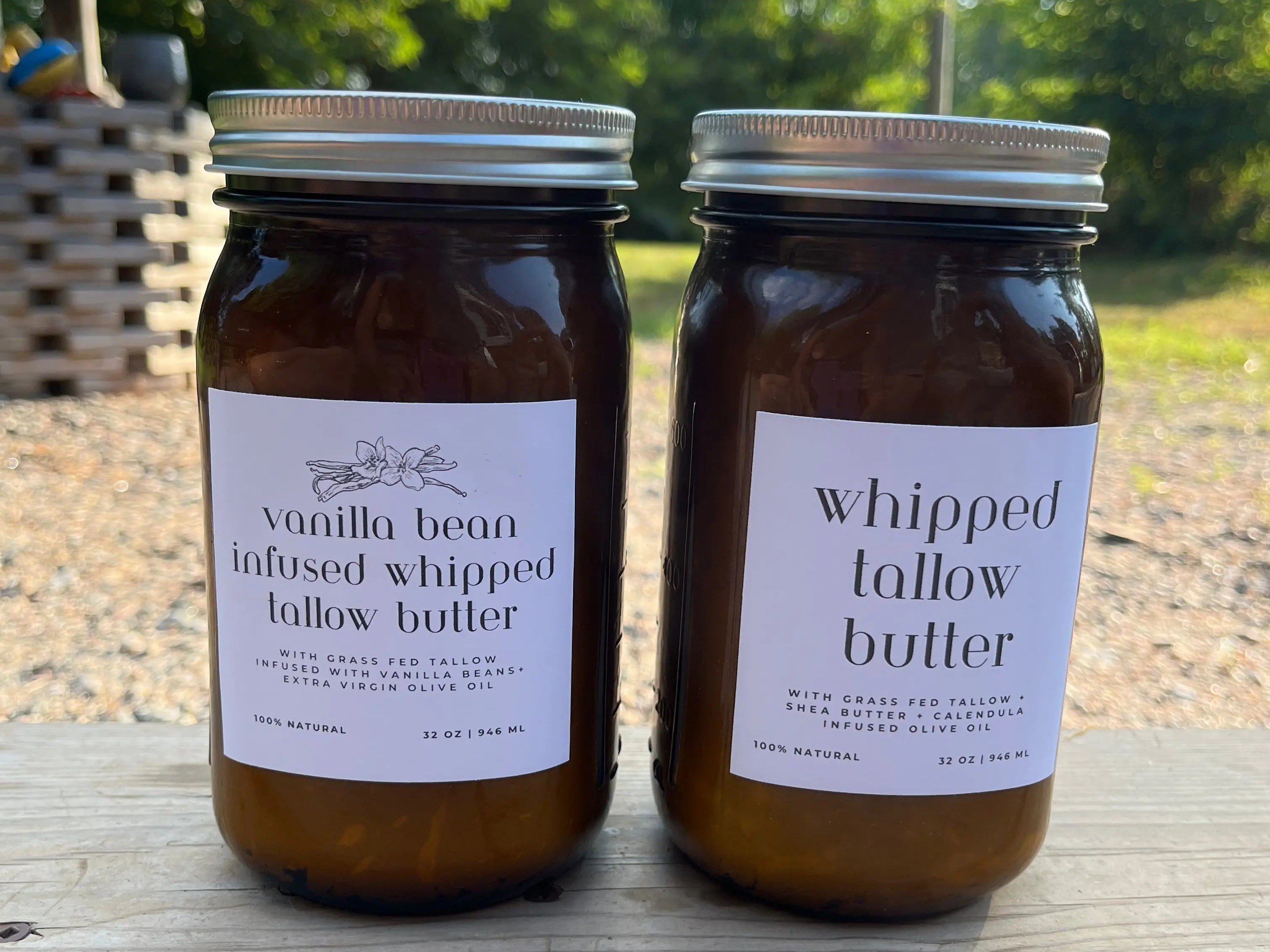 Two jars of whipped tallow butter on a wooden surface with a natural outdoor background.