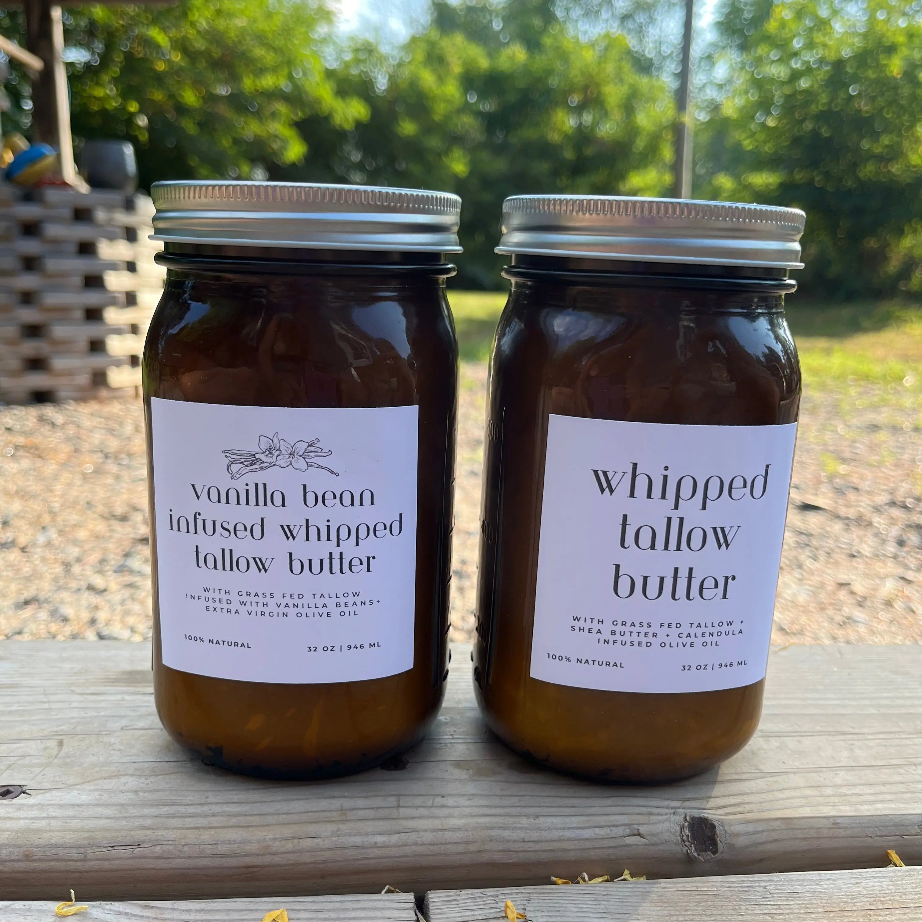 Two jars of whipped tallow butter on a wooden surface with a natural outdoor background.