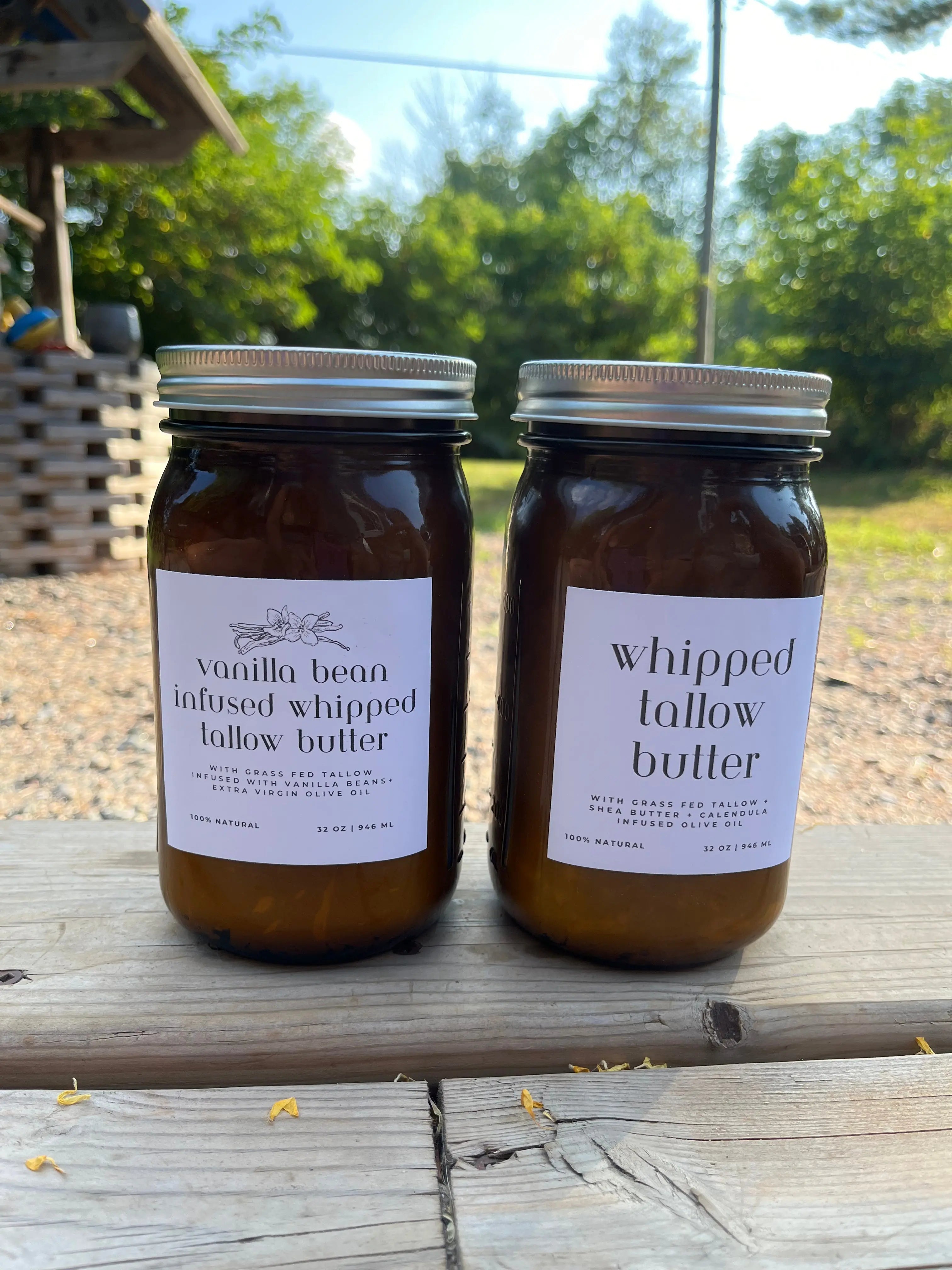 Two jars of whipped tallow butter on a wooden surface with a natural outdoor background.