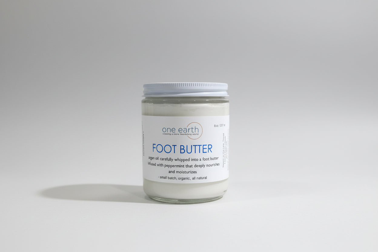 Jar of 'one earth' foot butter on a gray background