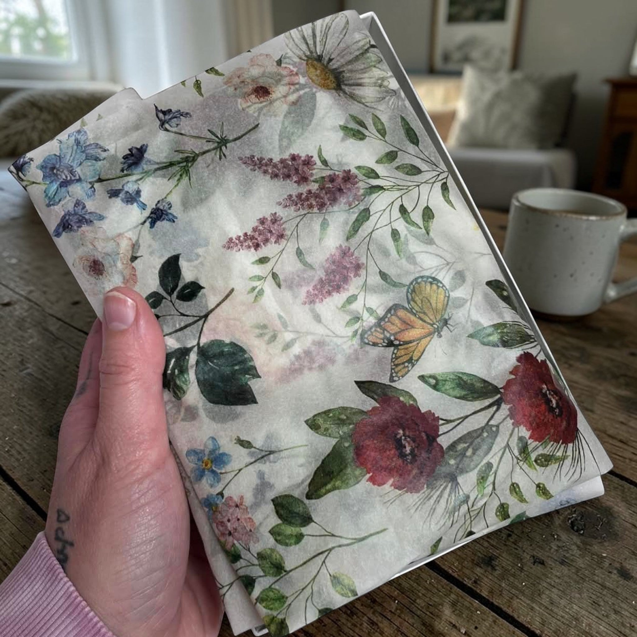 Floral notebook held by a hand on a wooden surface with a blurred background
