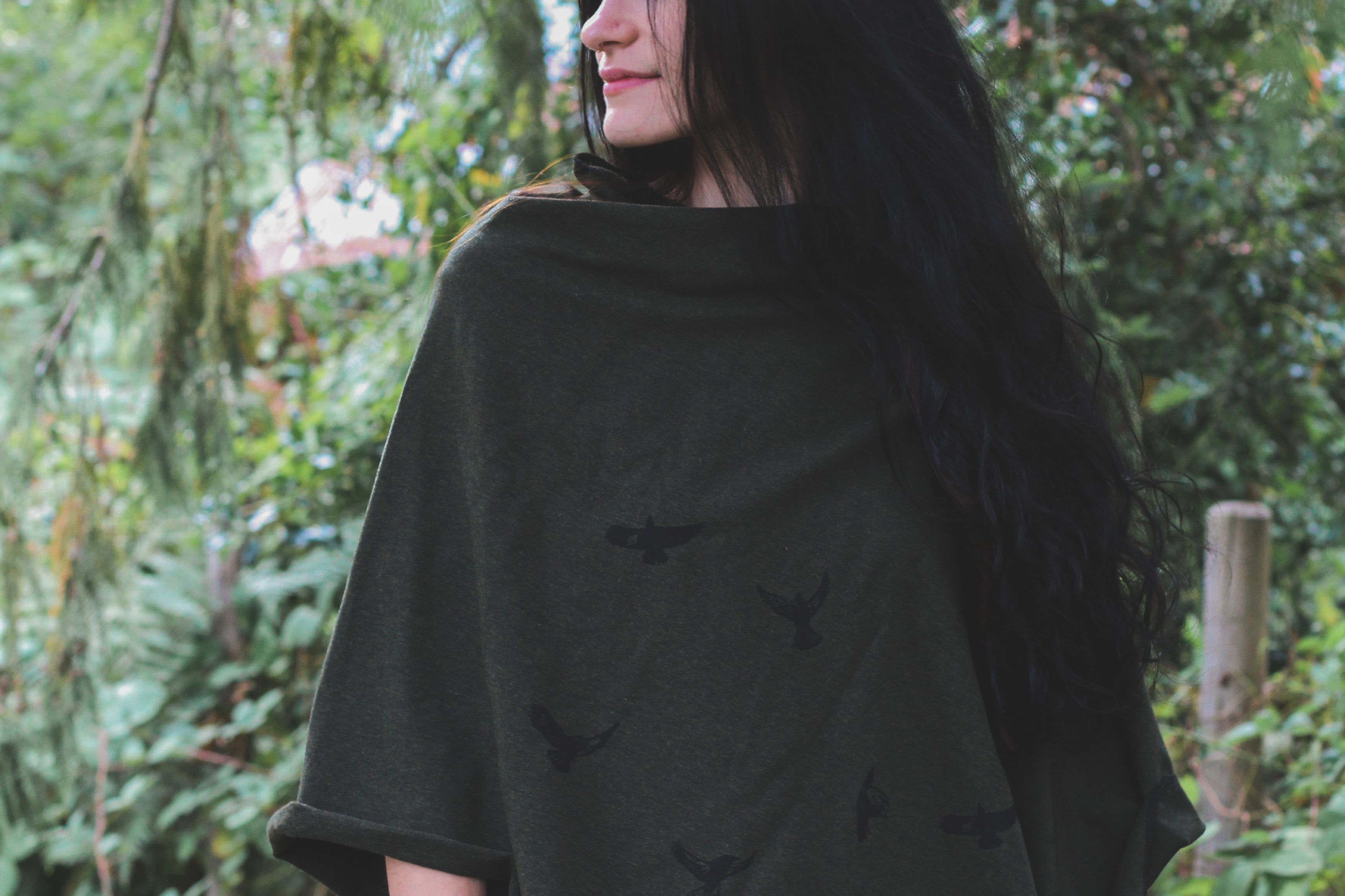 Woman wearing a black poncho standing in a forest
