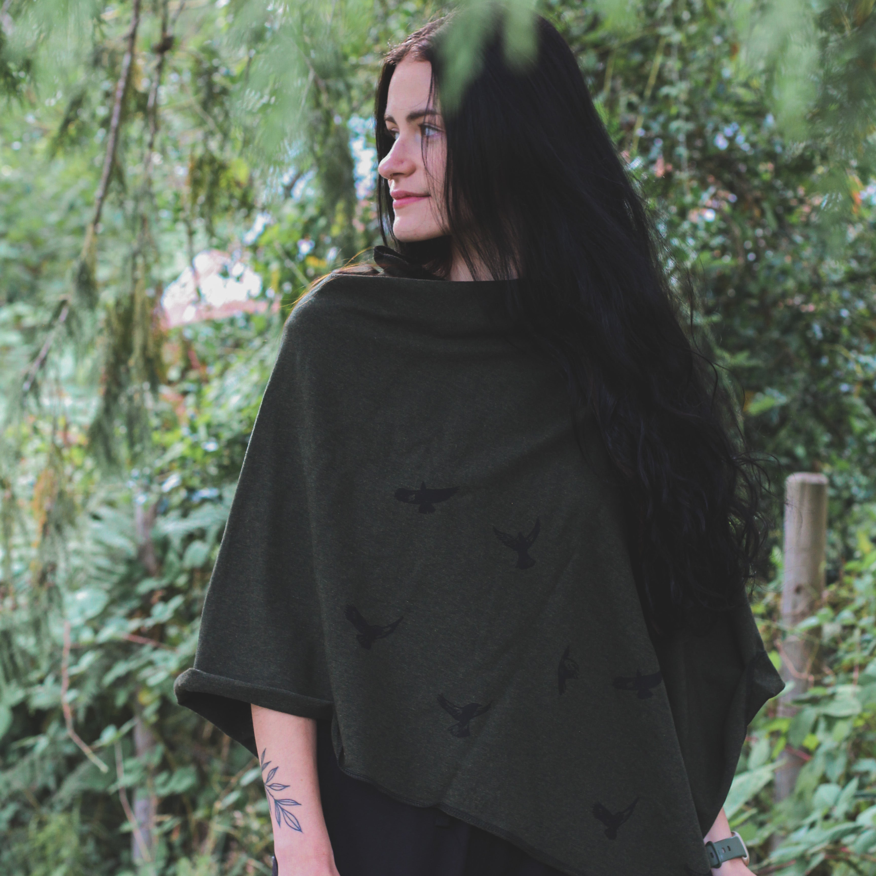 Woman wearing a black poncho standing in a forest