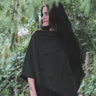 Woman wearing a black poncho standing in a forest