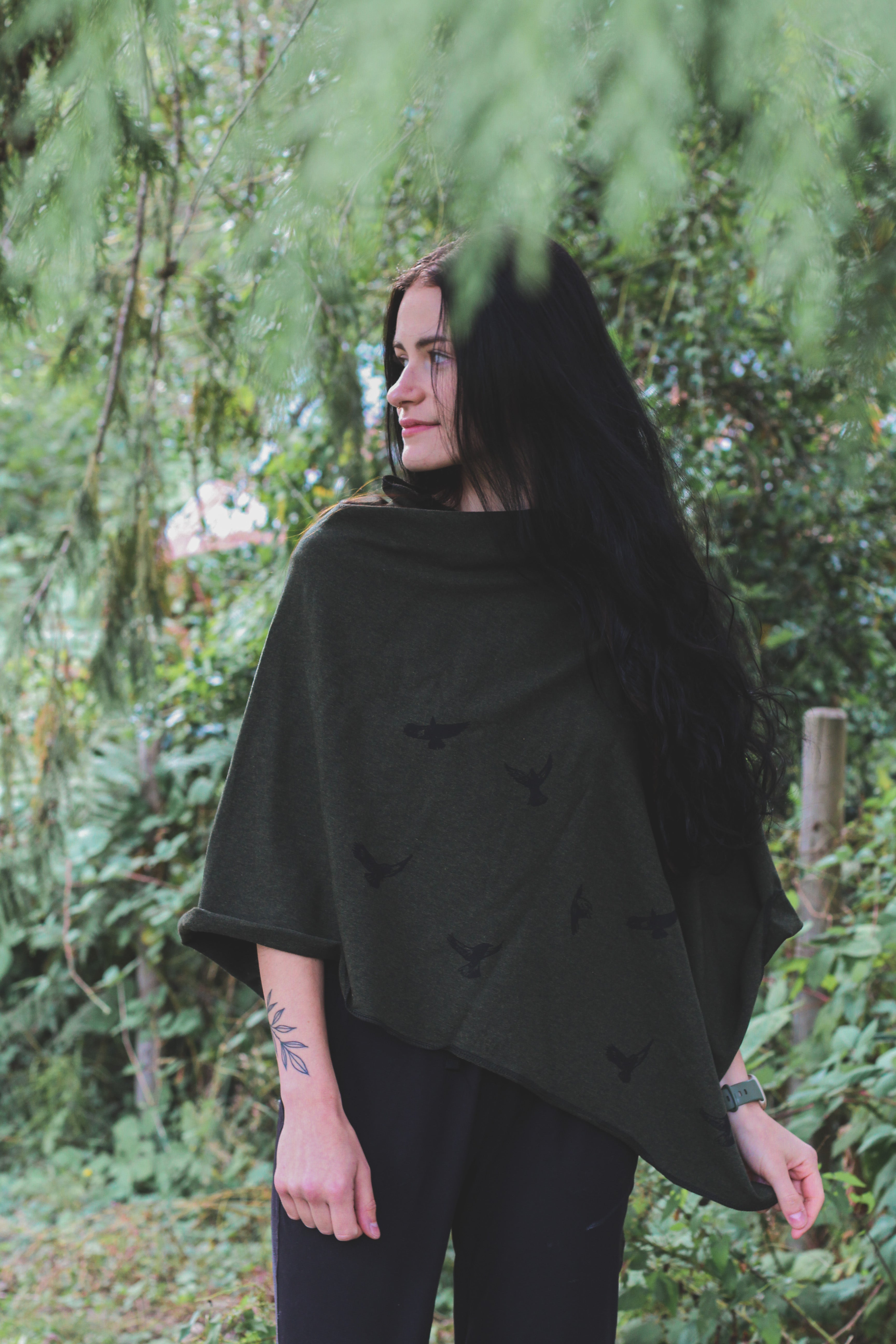 Woman wearing a black poncho standing in a forest