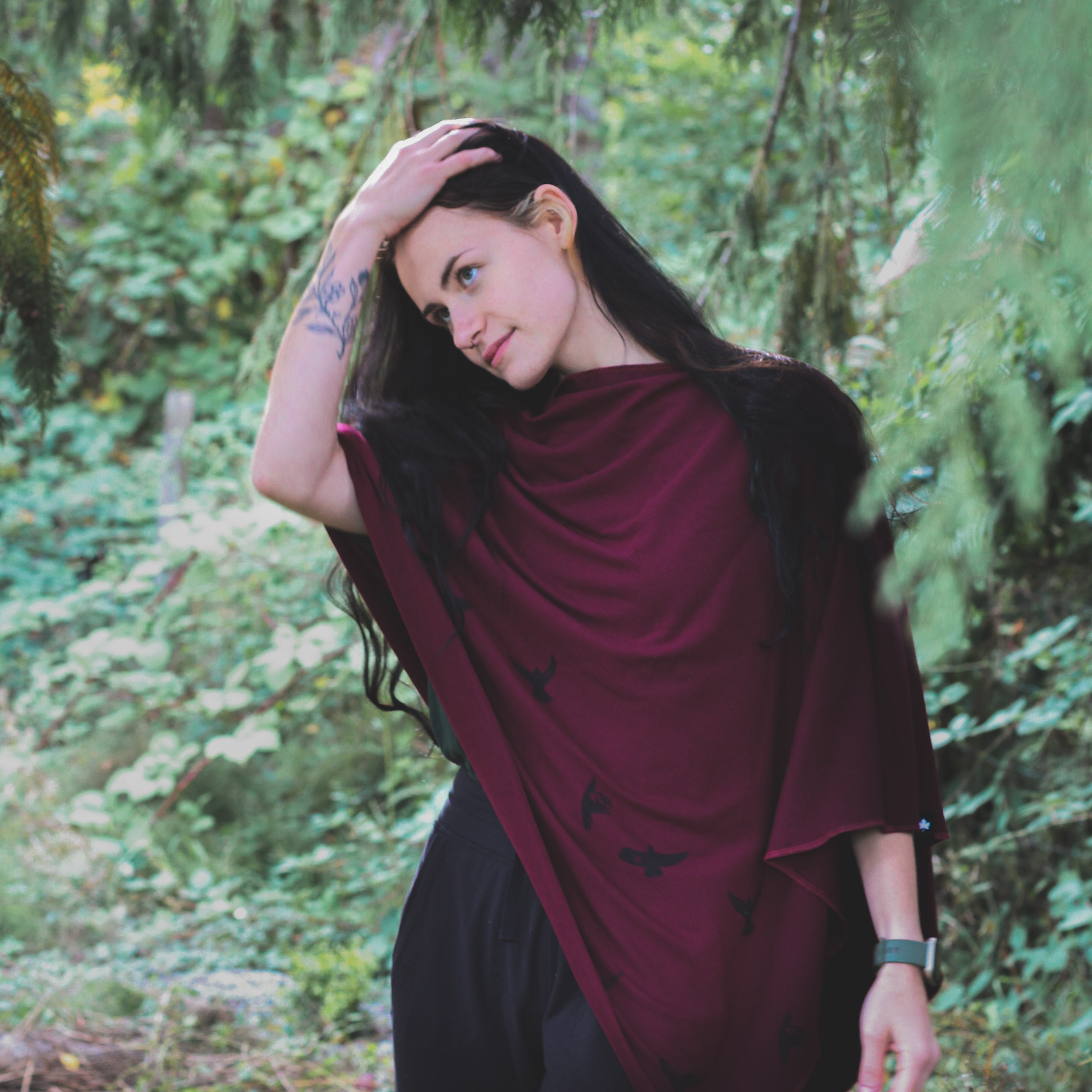 Woman in a burgundy shawl standing in a forest