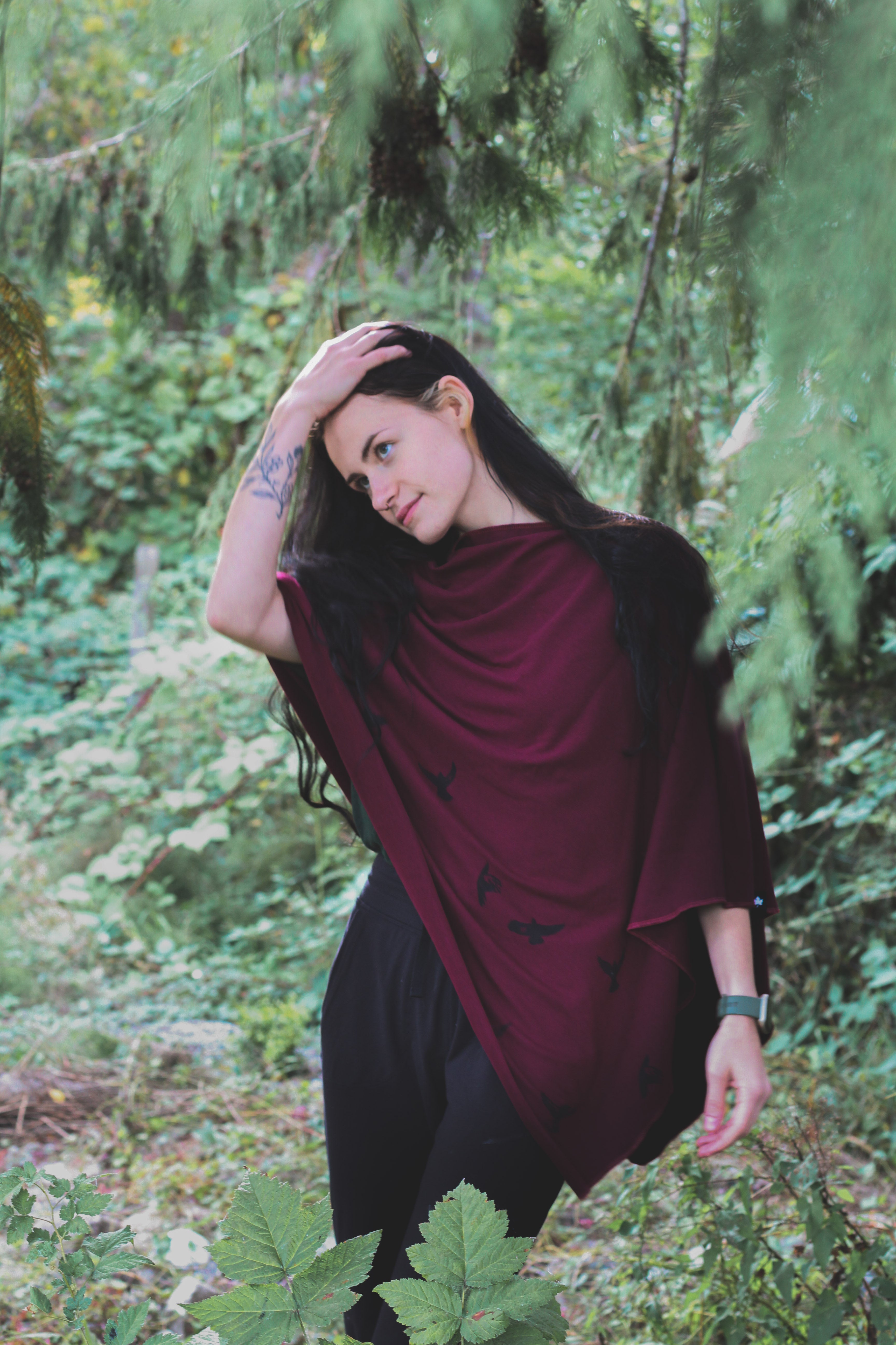 Woman in a burgundy shawl standing in a forest
